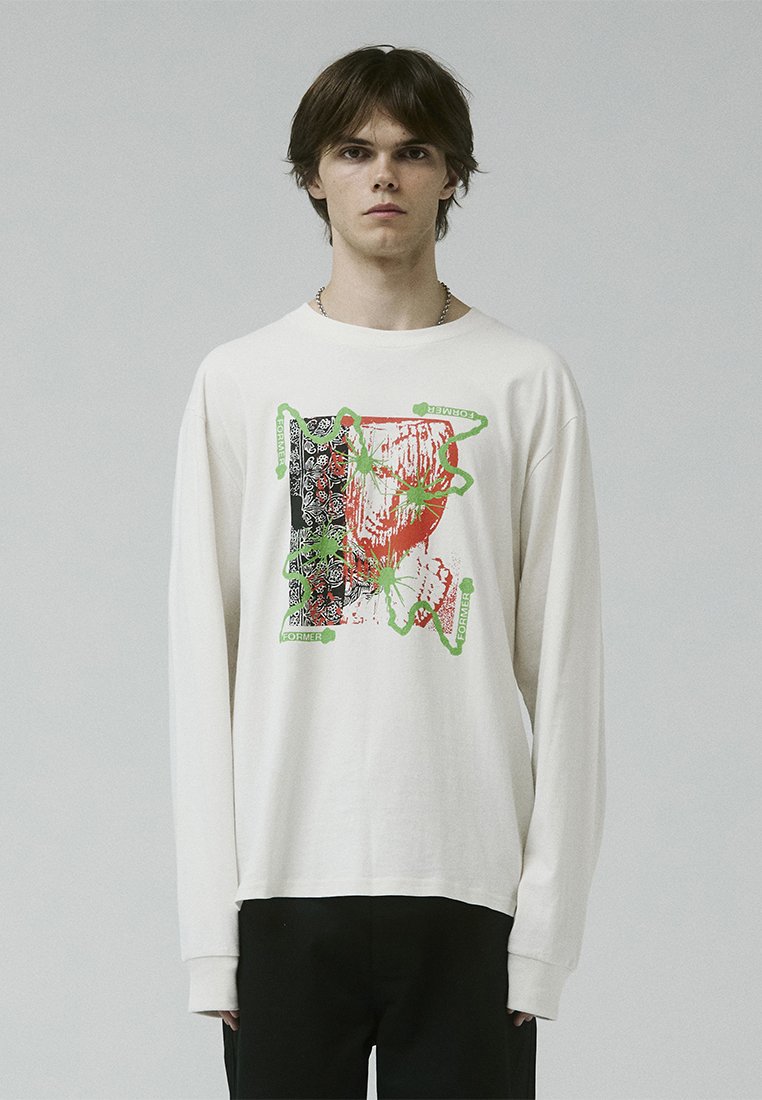 Camisa de manga larga color crema con un estampado gráfico en negro, rojo y verde, con elementos abstractos y acentos de texto. Tejido de algodón suave.