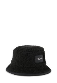 Chapeau seau noir en tissu molletonné texturé, avec une étiquette noire cousue comportant une inscription en lettres blanches affichant "HUGO."
