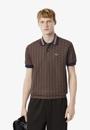 Brown patterned polo shirt with a navy ribbed collar and cuffs, featuring a green logo and a button placket. Lightweight fabric.