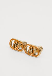Boutons de manchette dorés avec un design ovale entrelacé et un détail de logo découpé. Fini métallique lisse, texture polie.