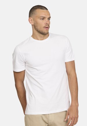 T-shirt en coton blanc avec un col rond classique, des manches courtes et un petit logo rouge au bas, présentant une texture lisse et douce.