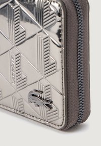 Portafoglio argentato testurizzato con motivi geometrici e zip nera. Presenta un sottile logo a croce in rilievo e accenti in tessuto grigio.