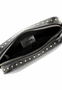 Schwarze Leder-Clutch mit goldenen Nieten am äußeren Rand, ausgestattet mit einem Reißverschluss und einem schwarzen Stofffutter mit Markenetikett.