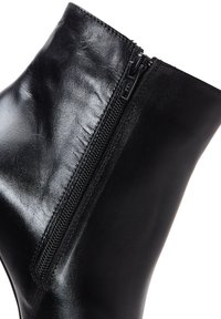 Bottines noires en cuir verni, dotées d'une fermeture éclair latérale, d'une texture lisse et d'un design ajusté qui se rétrécit à la cheville.