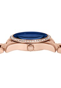 Montre en or rose avec un cadran en verre bleu, entourée d'une lunette incrustée de cristaux. Présente un logo MK distinct sur le côté.