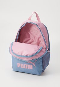 Mochila de tela rosa y azul, con una solapa delantera que presenta un logo de Puma rosa, bolsillos laterales de malla y un interior suave y forrado.