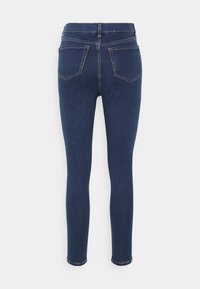 Jeans skinny de ganga azul escura com cintura alta, dois bolsos traseiros, costura em contraste e bainhas de pernas estreitas. Textura suave, design clássico.