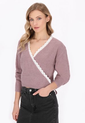 Hellblauer Wickelpullover mit einer gewellten weißen Kante, dreiviertellangen Ärmeln und einer strukturierten Strickoberfläche, kombiniert mit einem schwarzen Rock.