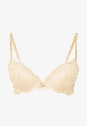 Beige kanten beha met golvende randen, onderdragen ondersteuning en subtiel bloemenpatroon. Heeft een klein strikje en decoratieve hardware in het midden.