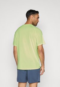 Ανοιχτού πράσινου χρώματος αθλητικό μπλουζάκι κοντομάνικο με στρογγυλή λαιμόκοψη και ελαφρώς χαλαρή εφαρμογή. Διαθέτει ανακλαστικές λεπτομέρειες στην πλάτη.