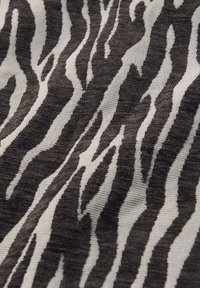 Svart och vit zebramönstrad textil med upphöjda mönster som skapar en taktil randig yta.