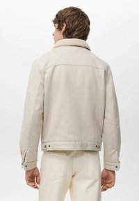 Beige Jeansjacke mit einem Lammfellkragen, geknöpften Bündchen und einer taillierten Passform, mit Rückpasse und sichtbaren Nahtdetails.