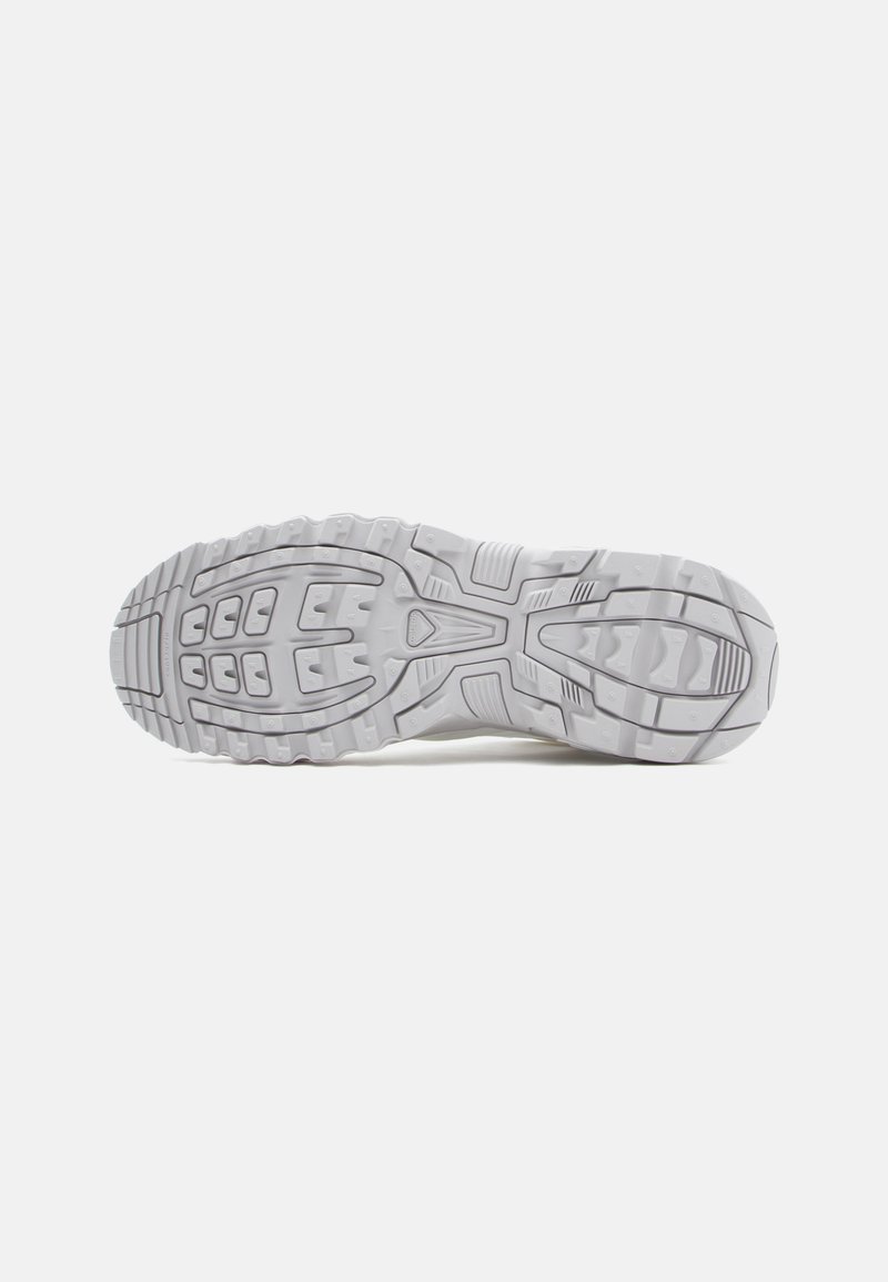 Weiße Sportschuhsohle mit einer strukturierten Gumm-Oberfläche, tiefen Profilen für Traktion und geformten Mustern für Flexibilität.