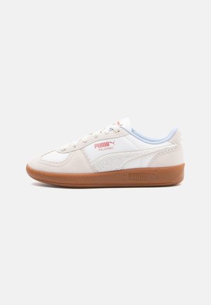 Low-top Puma Palermo sneaker in roomwit en wit met een gumzool en een rood Puma-logo op de zijkant en tong, gemaakt van gladde en gestructureerde materialen.