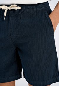 Shorts in corduroy blu navy con finitura testurizzata, dotati di vita con cordoncino, tasche laterali e dettagli di orlo cucito.