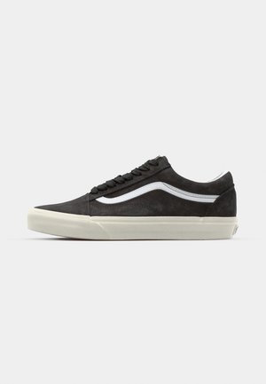 Schwarze Wildledersneaker mit einem weißen Wellenstreifen, flachen schwarzen Schnürsenkeln und einer cremefarbenen Gummisohle, mit niedrigem Profil und glatter Textur.