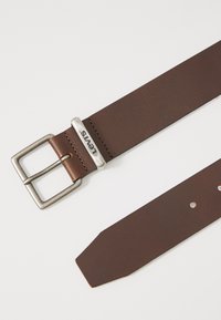Brauner Ledergürtel mit einer silbernen Metallschnalle und dem "Levi's"-Logo. Der Gürtel hat eine glatte Oberfläche und ein schräges Ende mit mehreren Einstelllöchern.