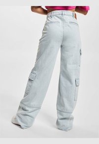 Pantalones cargo de denim de tiro ancho en azul claro, con múltiples bolsillos, un corte relajado y un acabado limpio sin hardware visible.