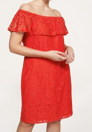 Robe rouge en dentelle, décolleté dégagé, longueur genoux, avec un motif floral et une coupe ample, mettant en valeur des détails complexes.