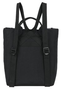 Mochila negra con correas ajustables, una superficie de tela texturada y un asa superior. Presenta un diseño minimalista y forma rectangular.