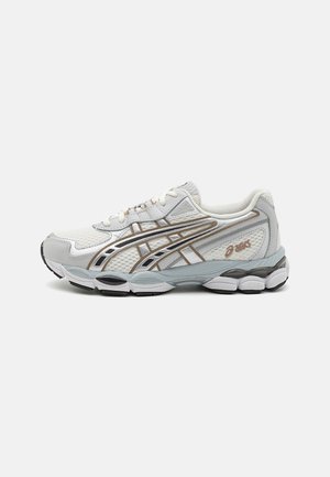 Sneaker grigio chiaro con tomaia in rete, dettagli in argento e oro, suola ammortizzata, branding laterale intricatamente progettato e suola in gomma testurizzata.