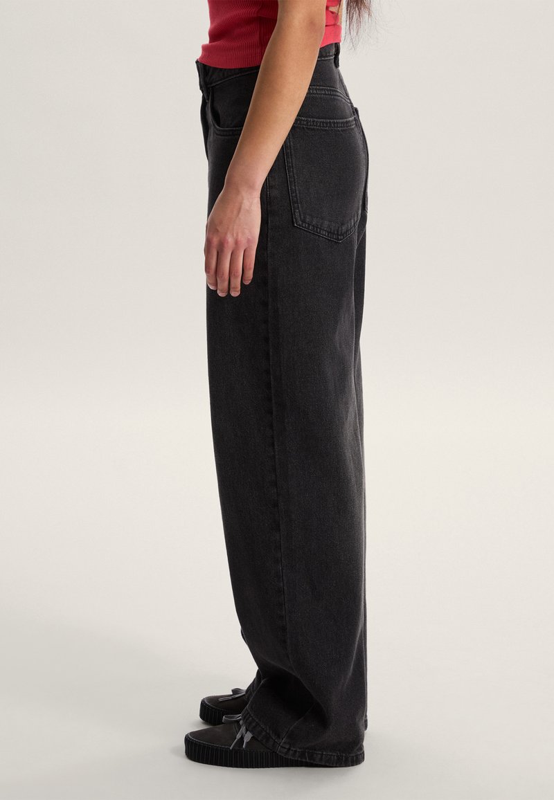 Černé džíny s vysokým pasem a širokými nohavicemi vyrobené z denimu, s klasickým pětikapsovým designem a hladkou texturou s jemnými detaily prošití.