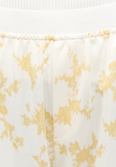 Λευκό ύφασμα με ανοιχτοκίτρινες αφηρημένες κηλίδες, με ελαστική ζώνη και ραμμένη ραφή στη μέση.