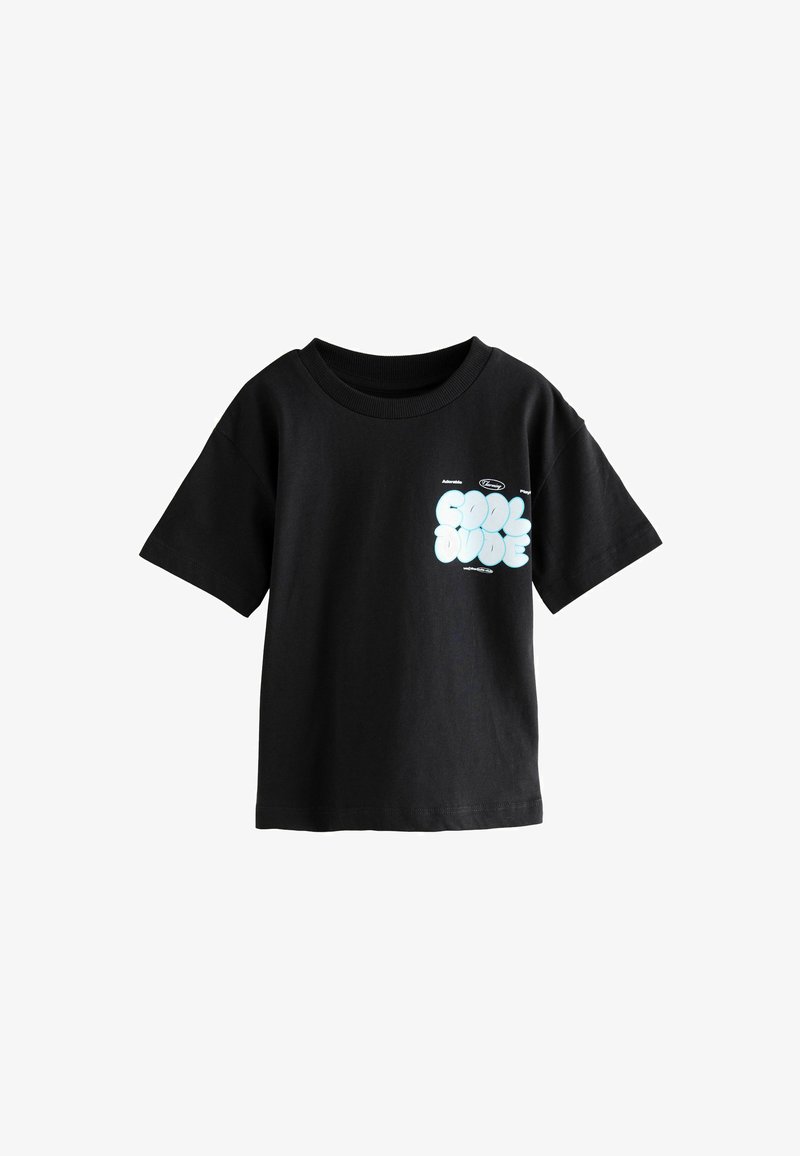 Musta puuvillapaita, jossa on lyhyet hihat ja pyöreä pääntie. Huomiota herättävä valkoinen grafiikkateksti "COOL DUDE" vasemmassa rintakehän kohdalla.