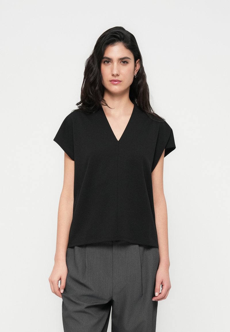 Haut noir à manches courtes avec un col en V, coupe décontractée, fabriqué en tissu léger, présentant un design épuré et minimaliste ainsi qu'une texture lisse.