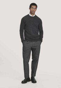 Dunkelgrauer Pullover mit Rundhalsausschnitt, kombiniert mit hellgrauen, plissierten Hosen. Schwarze Stiefeletten runden das Outfit ab. Glatte Textur.