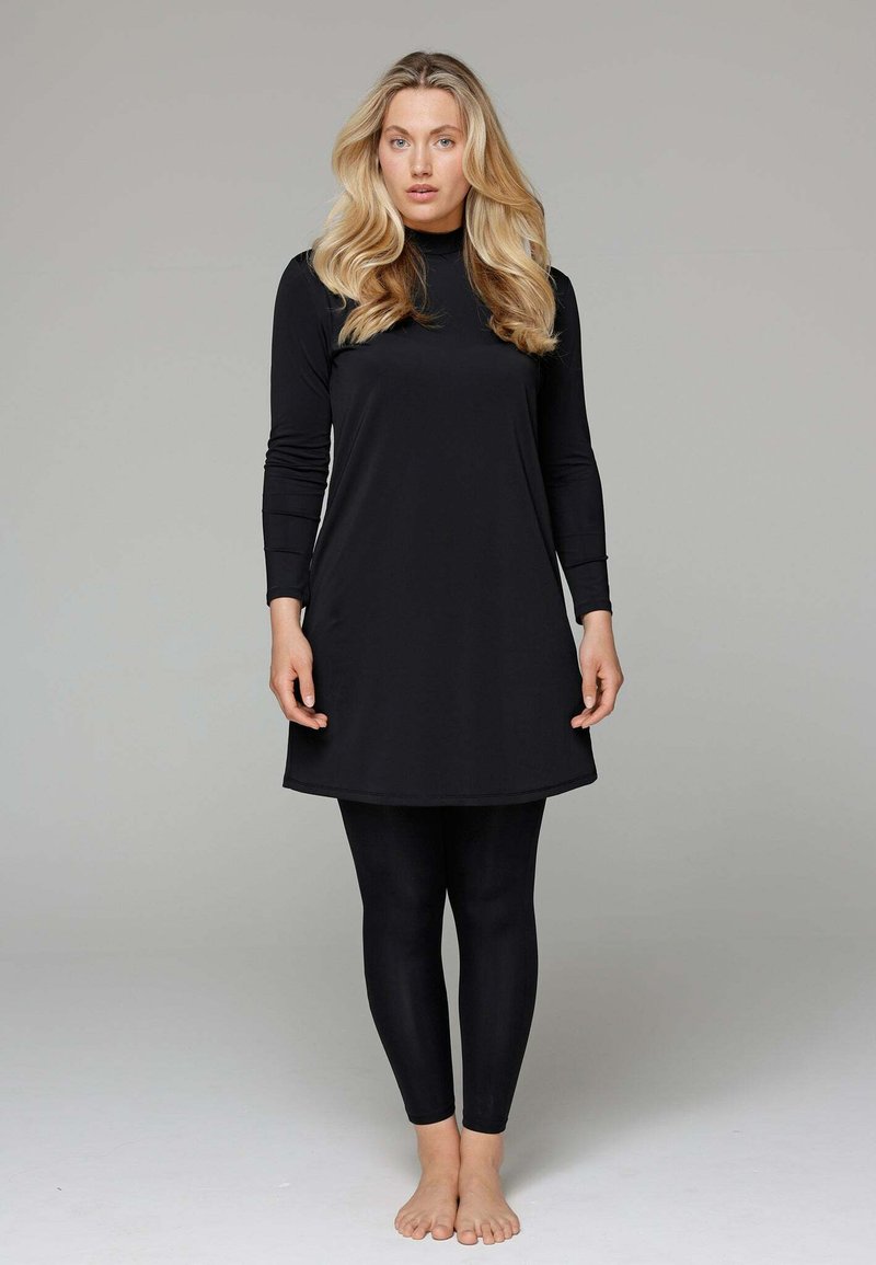 Zwarte lange mouw tuniek met een hoge halslijn, gecombineerd met zwarte legging. Gemaakt van een glad materiaal, met een eenvoudig, gestroomlijnd ontwerp.