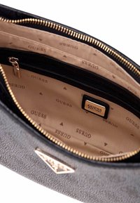 Borsa Guess nera con texture, con cerniera dorata, foderata internamente in beige con loghi Guess stampati, e una tasca interna con zip e placca con logo.
