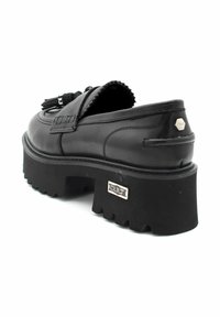 Zwarte leren instapschoenen met een chunky, gestructureerde zool. Voorzien van een kwastje als accent en gevlochten stiksels. Metalen hardware toont de merknaam.