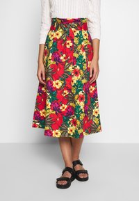 Blommig midiklänning med livliga röda, gula och lila blommor, med en figurnära midja, sidofickor och ett lätt tyg.