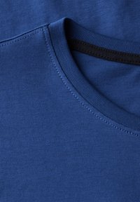 Sininen puuvillapaita, jossa on ribbauscrew-kaulus. Paita on sileätekstuurinen ja siinä on tummat ompeleet kauluksessa.