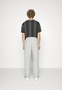 Kortärmad, svart och grå randig t-shirt som sätts ihop med ljusgrå sweatpants med elastisk midja och snörning vid anklarna.