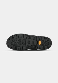 Black rubber outsole with deep treads, featuring a prominent Vibram logo. Rugged texture designed for traction on various surfaces.