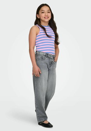 Girl standing and smiling, wearing a pink and blue striped sleeveless top, gray high-waisted jeans with a tied belt, and black flats.