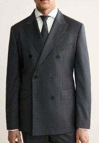 Giacca da suit doppiopetto grigio scuro con revers a punta, due tasche frontali e bottoni neri. Vestibilità su misura e texture liscia.