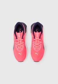 Ζευγάρι έντονα ροζ αθλητικά παπούτσια με μαύρη εσωτερική επένδυση, λευκές σόλες και το λογότυπο της Puma στην περιοχή των δακτύλων, απεικονιζόμενα από πάνω σε λευκό φόντο.