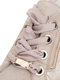 Baskets beige clair avec lacets en ruban de tissu passés dans des œillets métalliques et un détail de fermeture éclair dorée sur le côté.