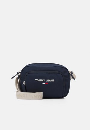 Granatowa torba na ramię Tommy Jeans z przednią kieszenią na zamek i beżowym regulowanym paskiem z wytłaczanym logo.