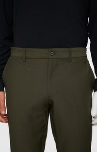 Oliwkowe spodnie z płaskim przodem, posiadające zapięcie na guzik i dyskretne boczne kieszenie, wykonane z gładkiego, lekkiego materiału.
