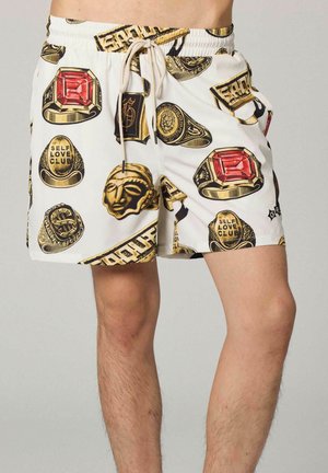 Weiße Shorts mit Kordelzug, mit goldenen Ringen, roten Edelstein-Designs und dem Schriftzug „Self Love Club“, getragen von einer Person von der Taille bis zur Mitte des Oberschenkels.