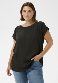 Culoare neagră, bluză lejeră cu mâneci scurte, decolteu rotund și deschideri laterale. Purtați cu blugi albaștri, având o textură netedă.