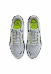 Scarpe da ginnastica bianche con una texture trapuntata, dettagli gialli brillanti nei lacci e nelle solette, e un logo Nike nero sul lato.