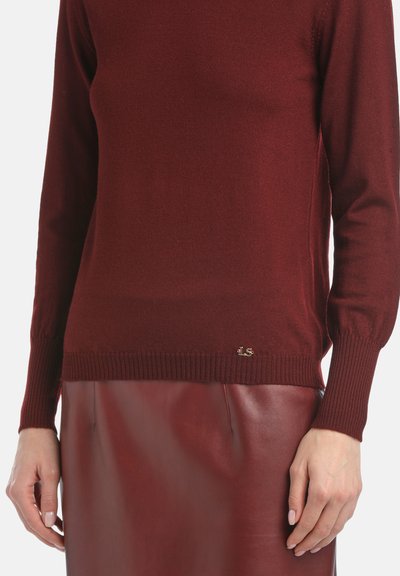 Pullover din amestec de lână, de culoare burgundă, cu manșete și tiv cu nervuri, având un mic accent cu logo auriu în colțul stâng. Asortat cu o fustă din piele în aceeași nuanță.