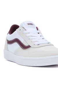 Sneaker Vans bianchi e beige con striscia laterale bordeaux, lacci bianchi e colletto imbottito, angolata per mostrare i dettagli frontali e laterali.