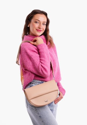 Beige Umhängetasche mit glatter Oberfläche und abgerundeter Klappe, ausgestattet mit einem abnehmbaren Riemen und dezentem Logodetail. Getragener strukturierter rosa Pullover.