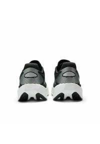Baskets de sport noires avec un dessus texturé, des accents argentés prononcés et une semelle noire et blanche avec un design géométrique.